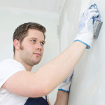 Male plasterer in uniform polishing the wall.